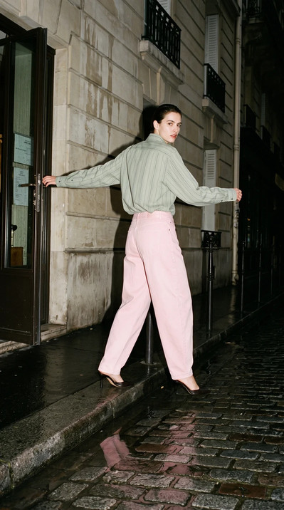 AI-generated on-model fashion photo: Sage shirt and pink trousers, wet cobbles
